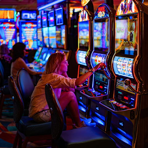 Young woman in a casino, playing on a digital slot machine game.